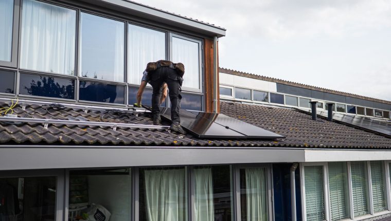technician installing solar panels on rooftop