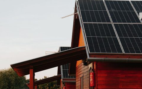 wooden house with solar panels at sunset