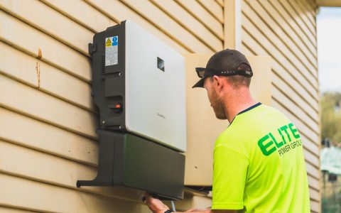 technician installing solar energy inverter outdoors