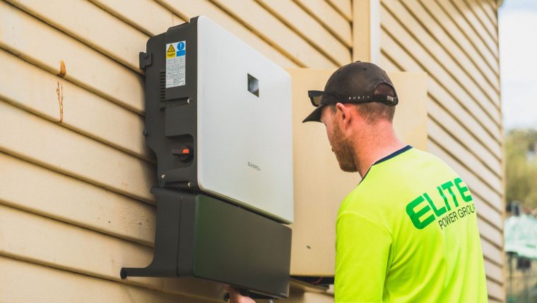 technician installing solar energy inverter outdoors