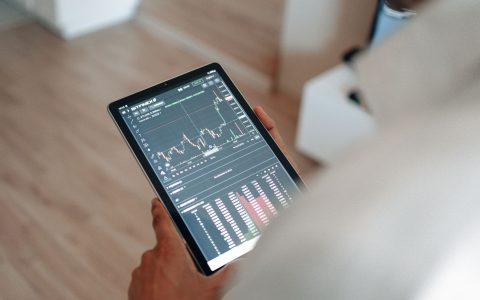 hand holding black tablet with graph on screen