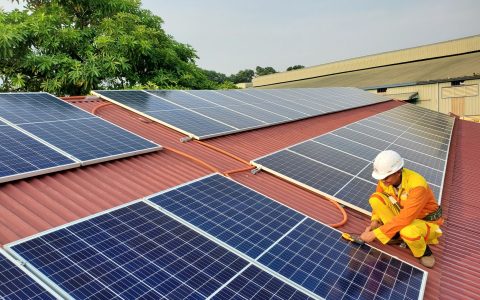 a male solar technician installing a solar panel