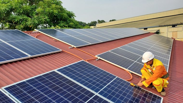 a male solar technician installing a solar panel