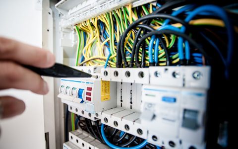 electrician fixing an opened switchboard