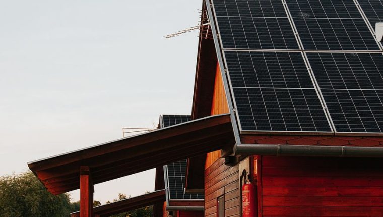 wooden house with solar panels at sunset
