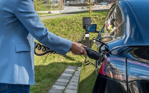 person charging electric car outdoors