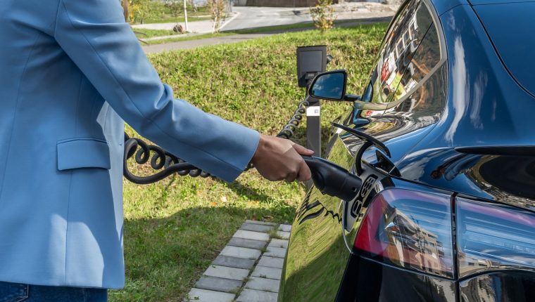 person charging electric car outdoors