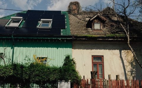 old house with solar panels and red fence