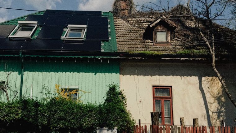 old house with solar panels and red fence