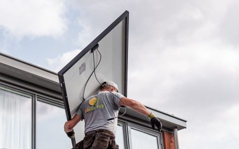 technician installing solar panel on rooftop