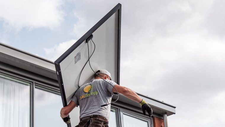 technician installing solar panel on rooftop